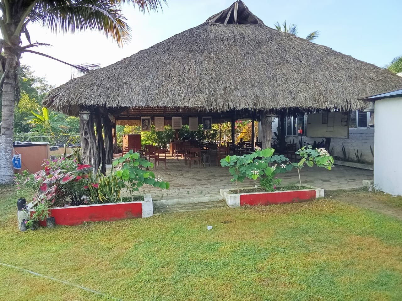 Comedor bajo palapa rodeado de jardín